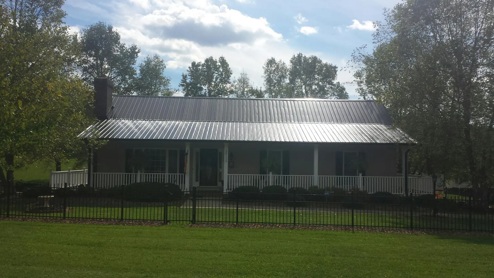 Gray metal roof on a brick ranch with a full width front porch — Gutter Guard Installation work by our crew in North Hampton